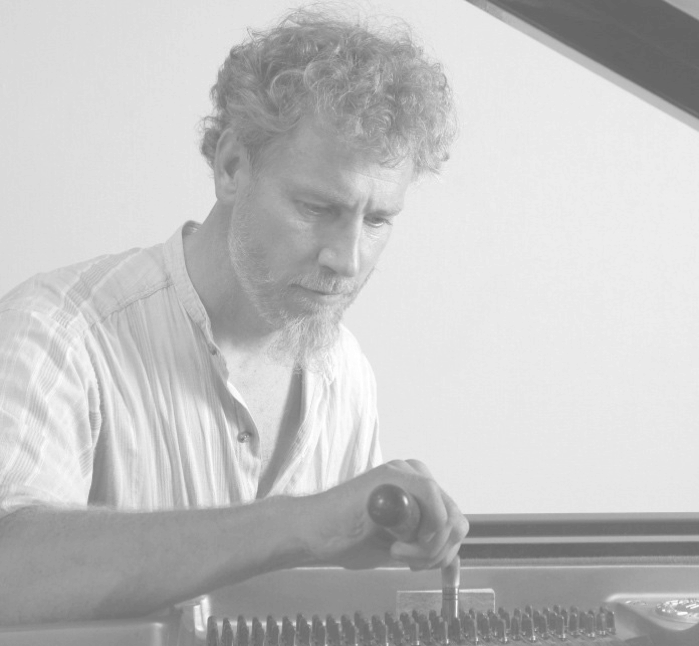 Björn Holmqvist i arbete vid ett pianos strängar